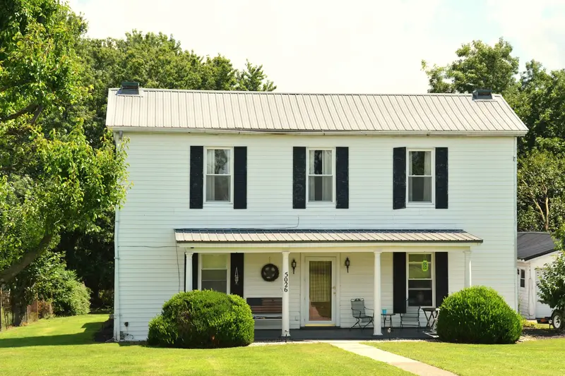 A two-story white house with black shutters and a front porch
